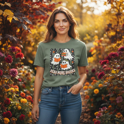 Between The Pages Boutique olive green t-shirt with a ghost reading books graphic, worn by a woman in a flower garden.
